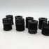 A group of small black cylindrical objects, resembling anti-vibration feet, are arranged on a white surface against a plain white background. Each features multiple circular ridges and has a uniform design with a central hole at the top. These could play a crucial role in vibration reduction for various devices. They are 3docity Anti-Vibration Feet for Bambu X1/P1 series (8pcs).