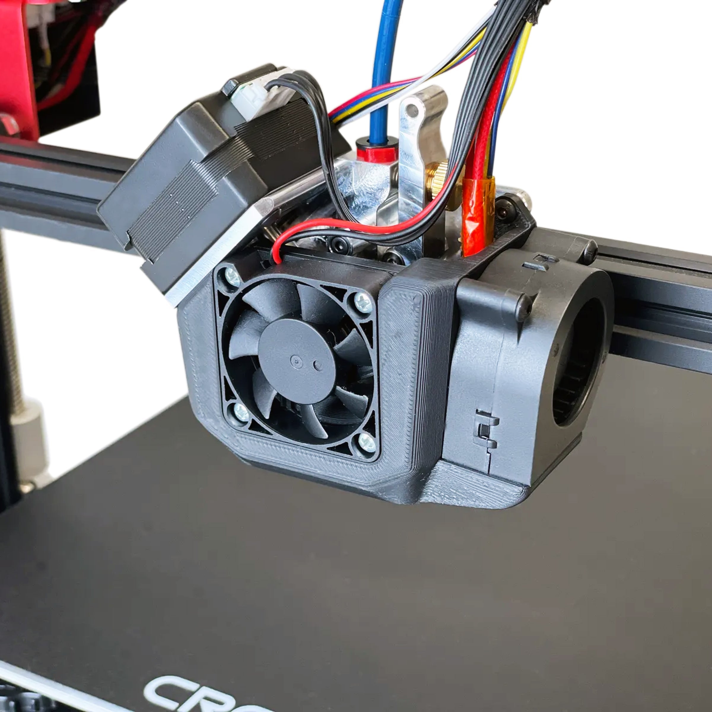 Close-up of the Micro Swiss NG Direct Drive Extruder for Creality CR-10S Pro V2 and CR-10 Max, featuring a small cooling fan, dual gear drive, and various colorful wires. The bed of the 3D printer is partially visible at the bottom with the letters "CRE" from the brand name.